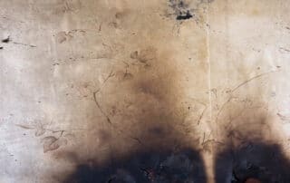Old wall with faded floral pattern and dark burn stains near the bottom.