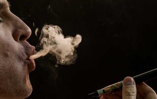 Person vaping and exhaling a cloud of smoke, asking 'Does Your Home Smell Like Pot?
