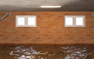 A flooded basement with brick walls and windows, highlighting the need for Emergency Basement Flooding Service to quickly address and restore water damage.