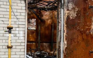 A rusted metal door in an abandoned building, requiring the expertise of fire damage contractors to assess and restore fire-damaged structures.