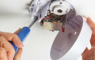 Installing a smoke detector on the ceiling, part of fire prevention tips.