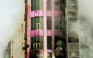 Smoke envelops a building during a fire incident, emphasizing the need for smoke damage restoration to remove residue, repair damage, and ensure safety.