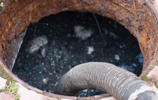 Sewer cleaning hose inside a manhole. Hazards of DIY Sewage Cleanup