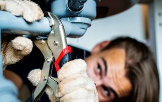 Plumber repairing sink with wrench, close-up view.