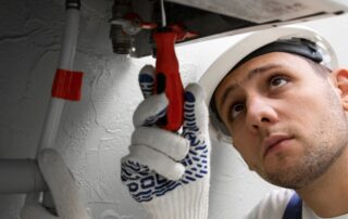 Plumber fixing pipes with wrench and gloves. Prevent Water Heater Flooding Tips