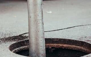 Drilling a pipe into an asphalt surface hole, highlighting the importance of sewage cleanup services to handle contamination and restore the area.