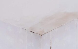 Ceiling corner with water damage stains visible.