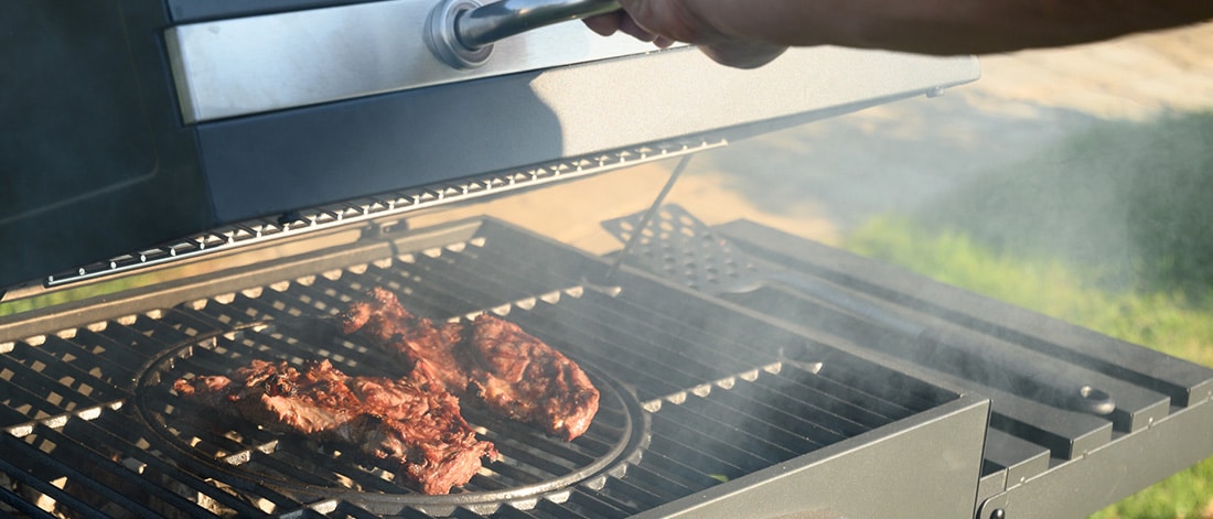 Backyard grill safely positioned away from the house with food cooking, showing fire safety practices to prevent house fires while grilling.