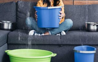 Person collects leaking water with buckets indoors.