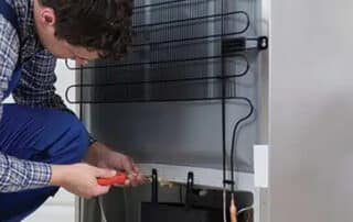 A technician repairing a refrigerator with tools, highlighting the risk of water damage from home appliances and the importance of timely repairs to prevent further issues.