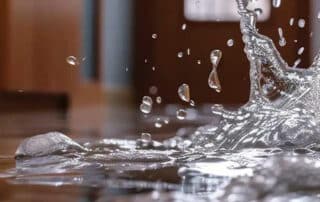 Splashing water on the floor indoors, highlighting factors that affect the cost of water damage restoration, such as severity, location, and materials involved.