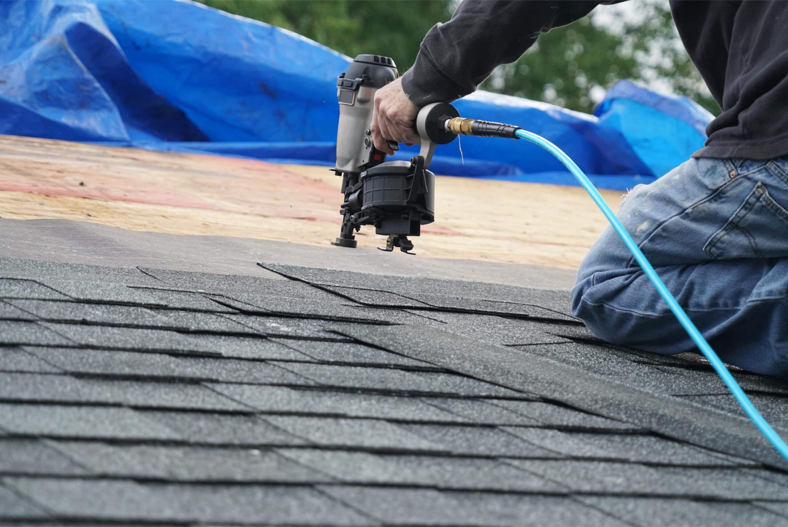 Worker using a nail gun for roofing installation, highlighting professional roof restoration services.